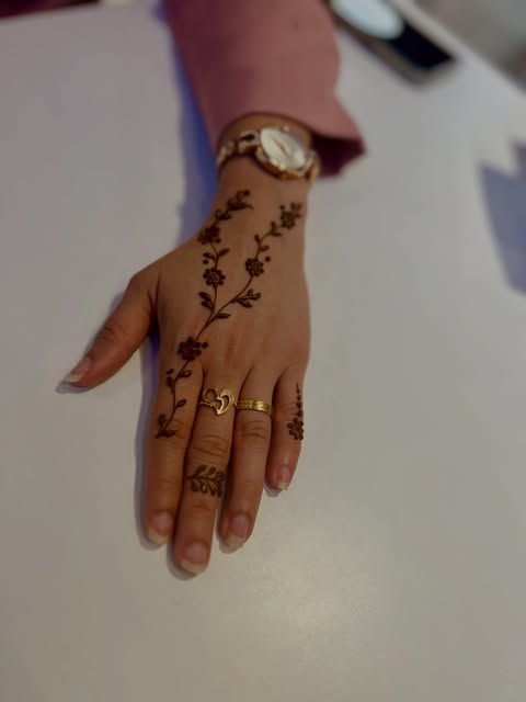 Fine minimal henna vine tracing the back of the hand and one finger