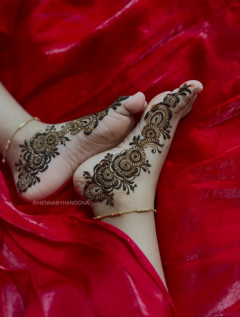 Bridal henna on the feet and ankles, photographed on red bridal fabric