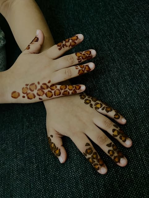 Modern spotted henna pattern running along the fingers and hand